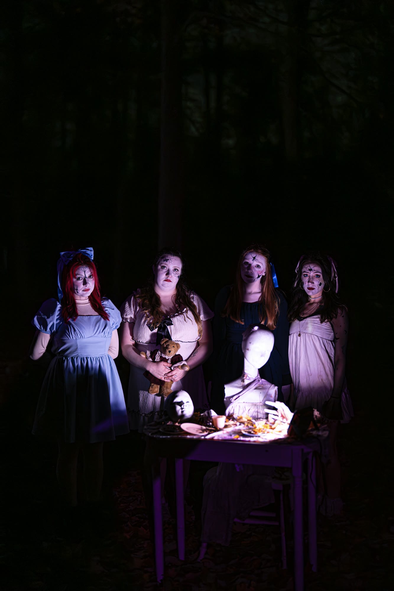 Four costumed doll-like characters seated at a table