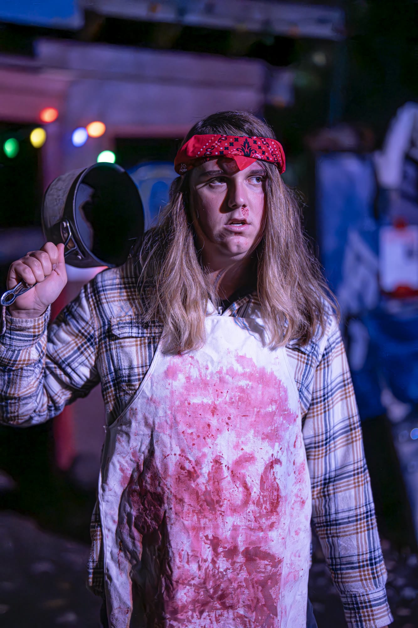 A costumed character in a bloody apron holding a frying pan
