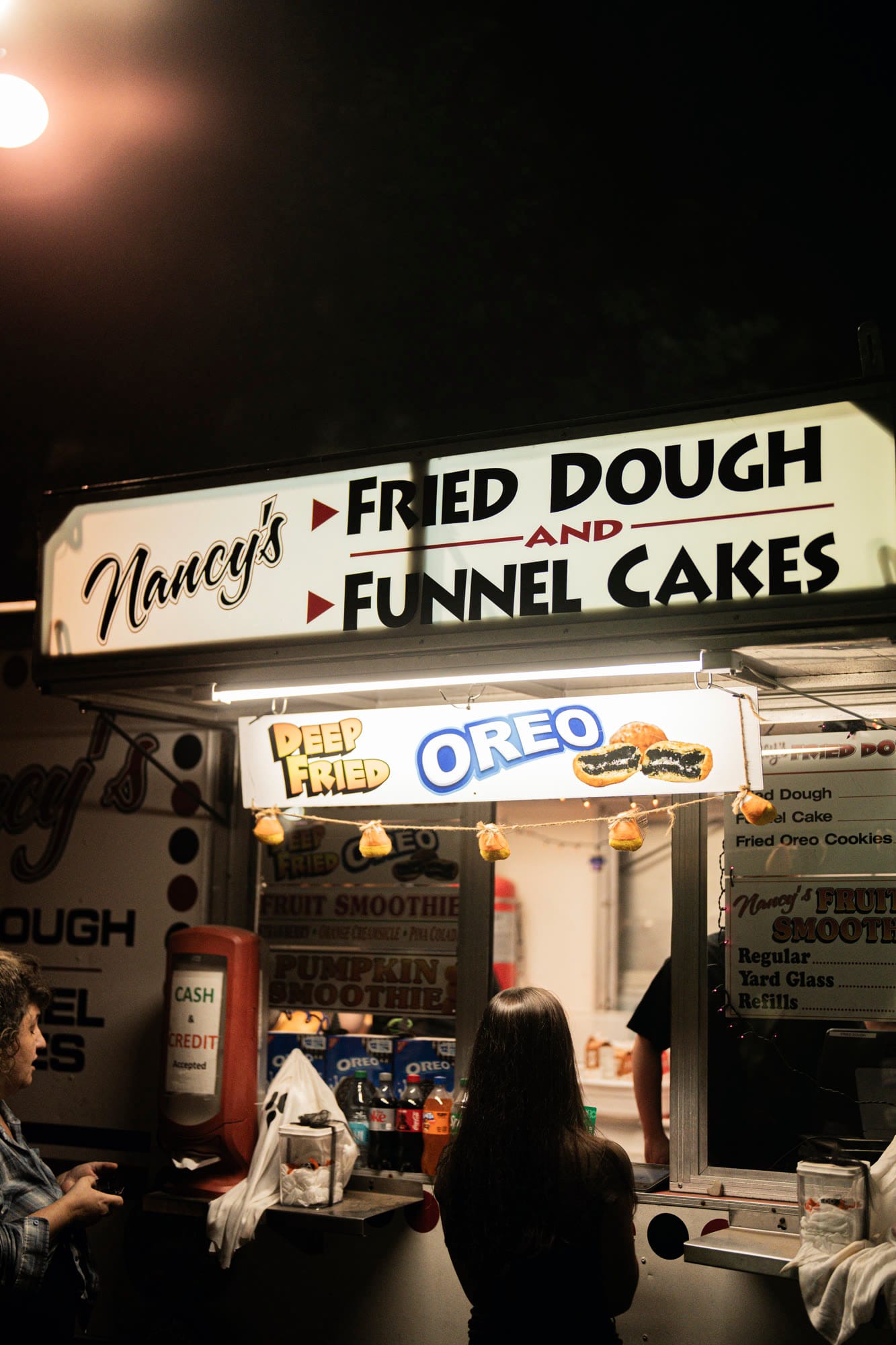 The Nancy's Fried Dough and Funnel Cakes stand lit up at night